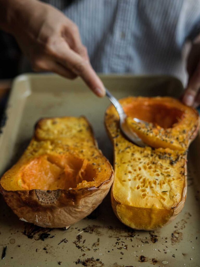 scooping out cooked flesh of butternut